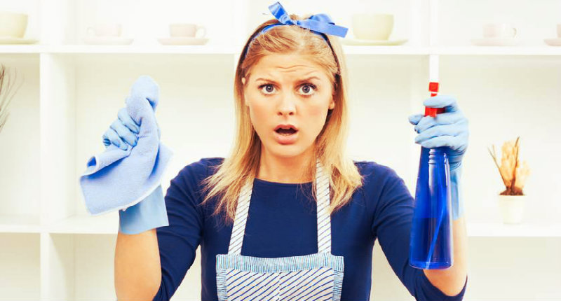 surprised woman holding spray bottle in one hand and rag