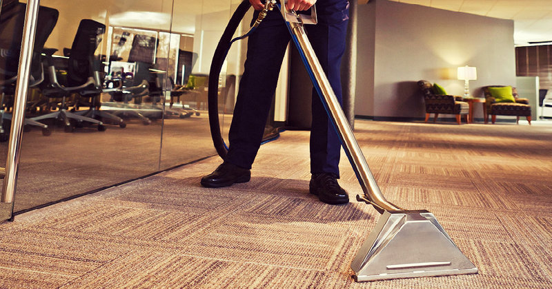 cropped image of a man vacuuming office carpet