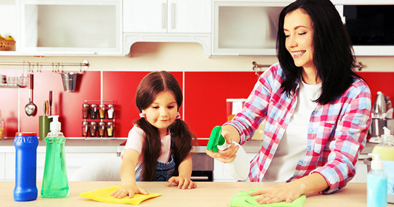happy mother and daughter wiping kitchen counter top