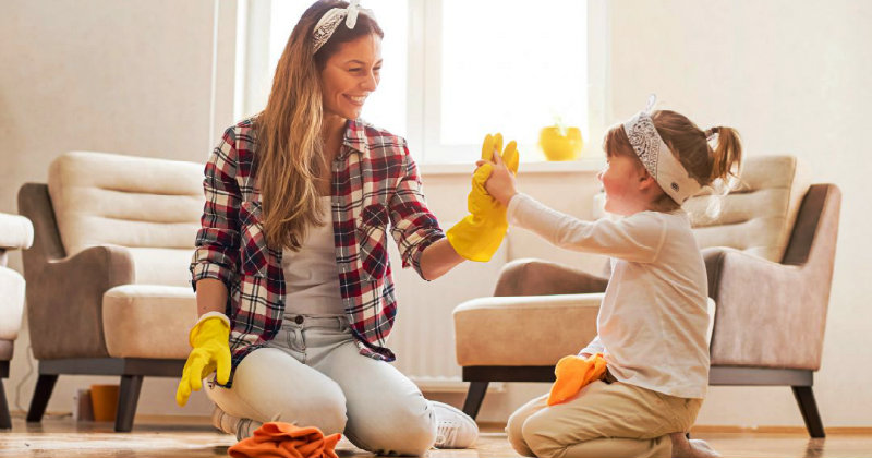 happy mother and daughter wiping the floor wearing protective gloves and giving high five