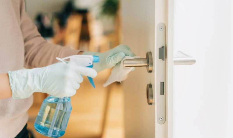 cropped picture of a man spraying solution on a door knob