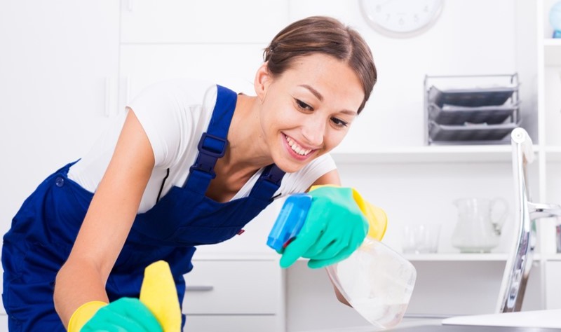 smiling woman holding a spray and a sponge