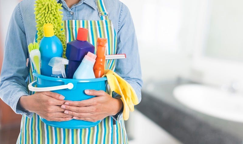cropped image of a woman holding a bucket full of chemicals and spray bottles