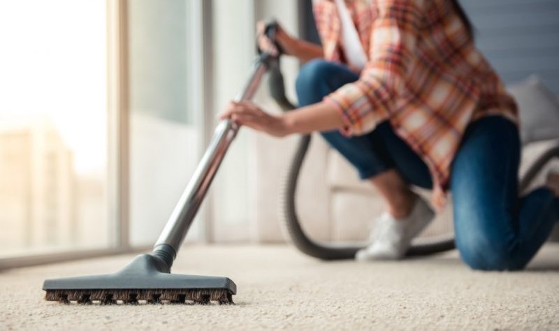 cropped image of a young woman holding a professional equipment to wipe a carpet