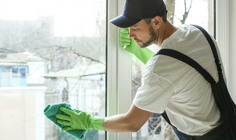 a young man wiping a window glass with a rag