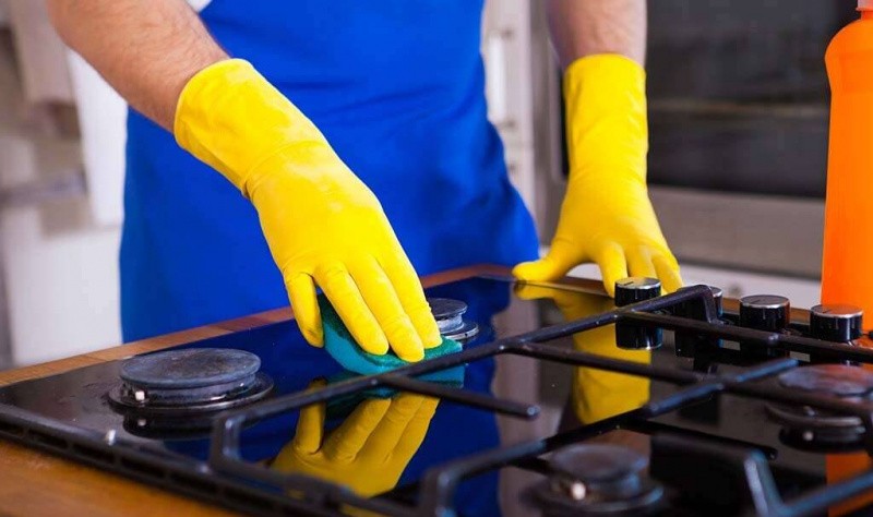 cropped image of a man wiping a gas stove with a rag