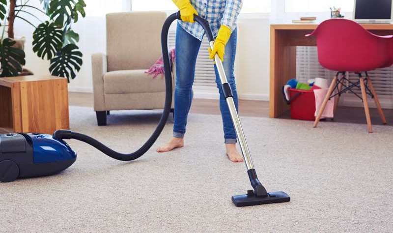 cropped image of a young woman vacuuming a carpet