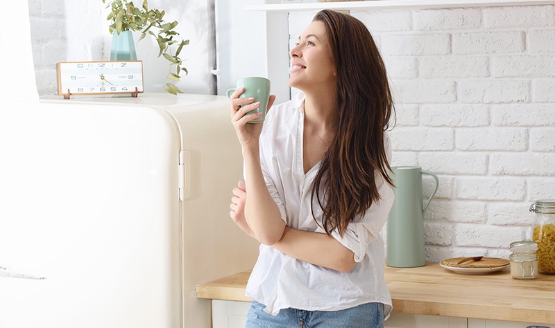 young woman enjoying her coffee in her kitchen