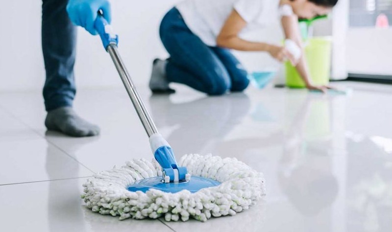 Cropped picture of a man moping the floor and a woman disinfecting the floor
