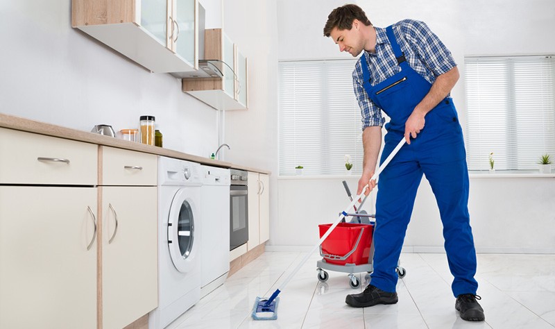 young professional wiping a kitchen floor with a wiper