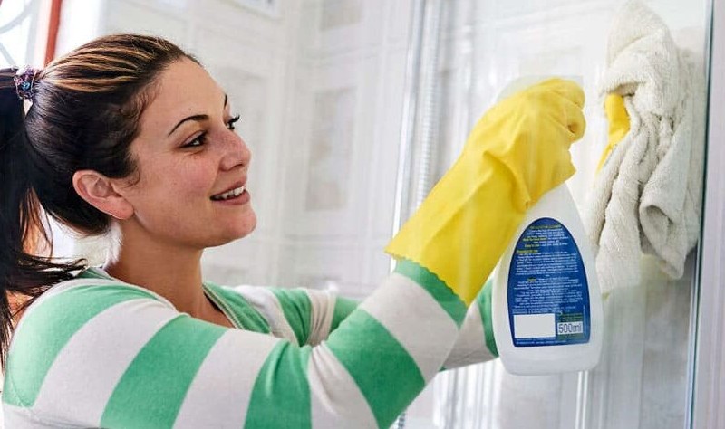 young woman wearing yellow gloves wiping a surface with a cloth mop