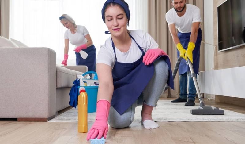 Two lady in white t-shirt, pink gloves and one boy in white t-shirt yellow gloves inside a room