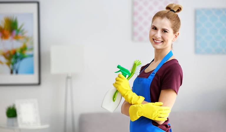 Woman in yellow gloves holding a bottle and smiling