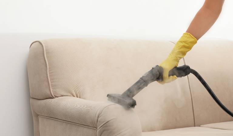 Hand of a woman in yellow gloves vacuuming on Upholstery