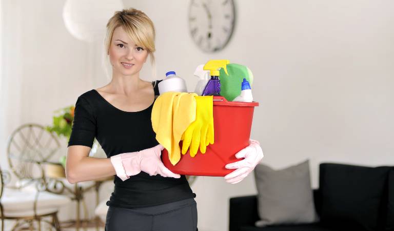 Woman in black dress holding a red basket filled with tools, products and cloth