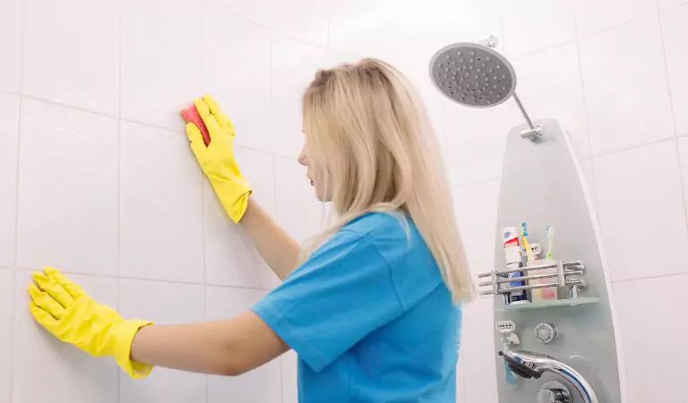 young woman cleaning the tiles of her bathroom