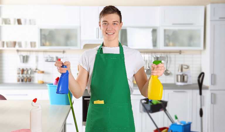 Man in white-green uniform holding blue bottle in one hand and yellow bottle in second hand.