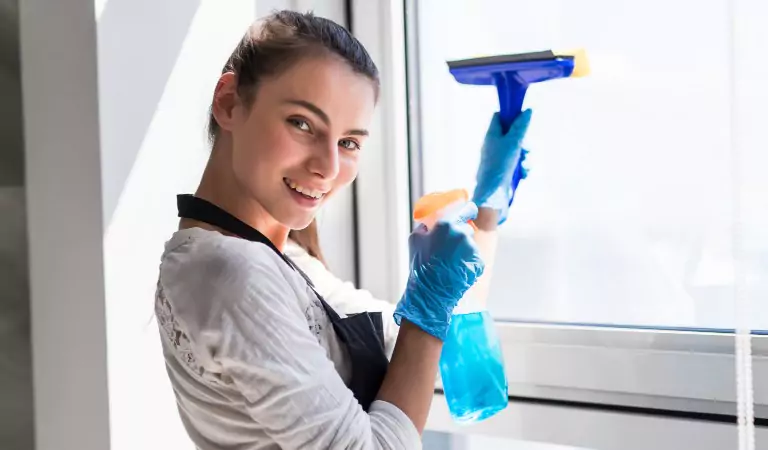 Young woman with a wiper ready to clean a window glass