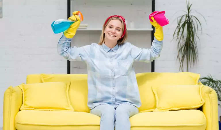 young woman sitting on a couch with some cleaning supplies