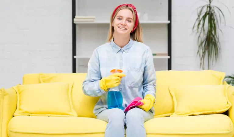 young woman sitting on a couch with some cleaning essentials