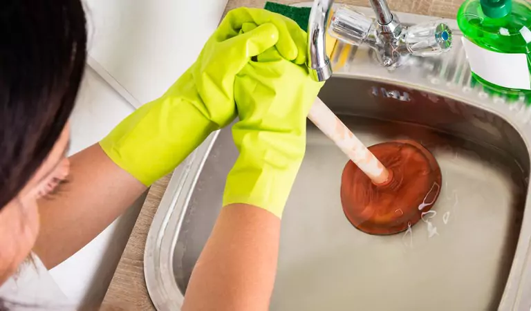 young woman trying to unblock a drain