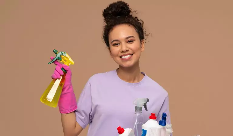 young woman is ready to clean her house holding some cleaning essentials in her hands