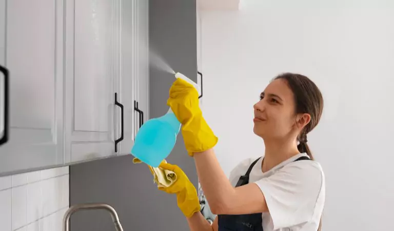 woman disinfecting a kitchen cabinet in her house