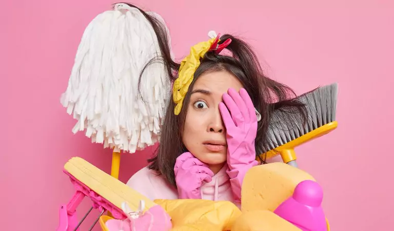 young woman with cleaning equipment looking worried