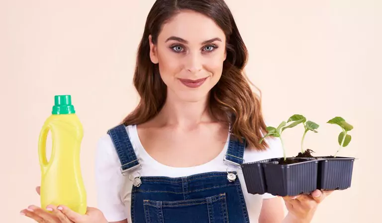 Young woman with a cleaning solution and a plant in her hands