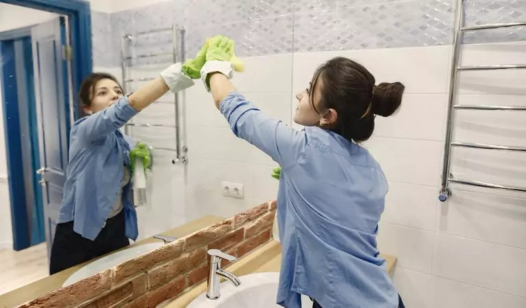 woman cleaning a bathroom mirror