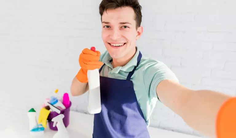young man with some cleaning supplies taking a selfie