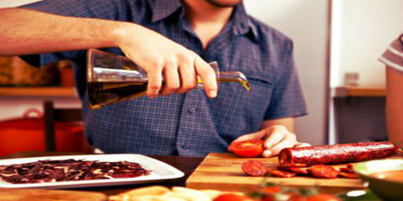 cropped image of a man pouring olive oil on beef