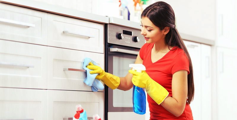 beautiful young woman wiping kitchen drawers