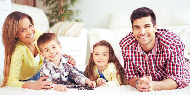 cute girl and boy lying on the carpet with their parents