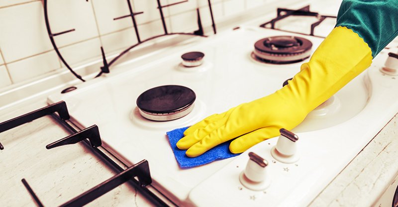 cropped image of a woman wiping stove top