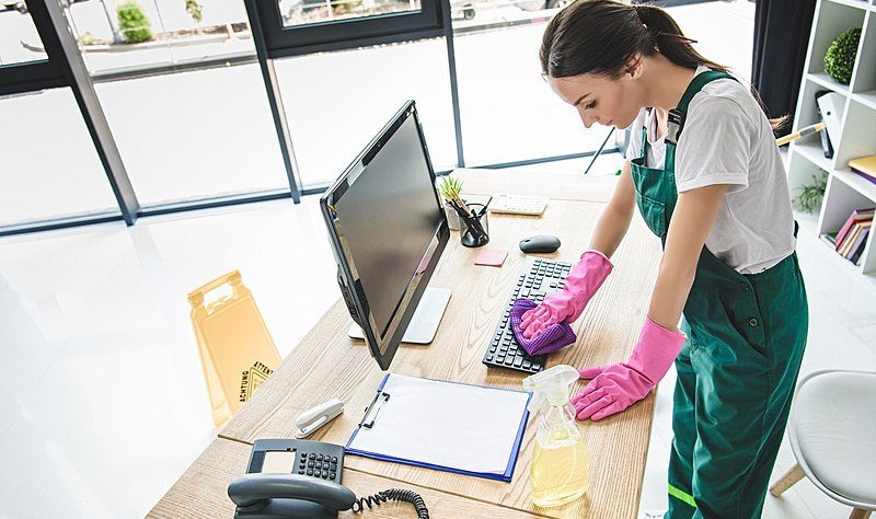 A woman is cleaning a office desk