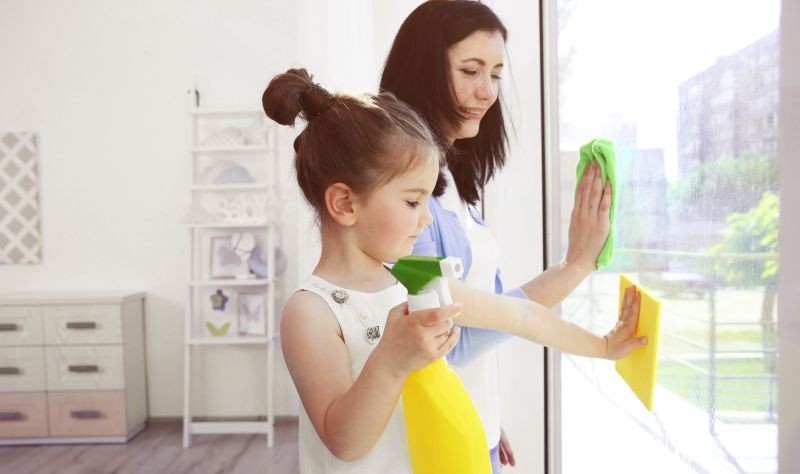 a woman is cleaning her window glass with her daughter
