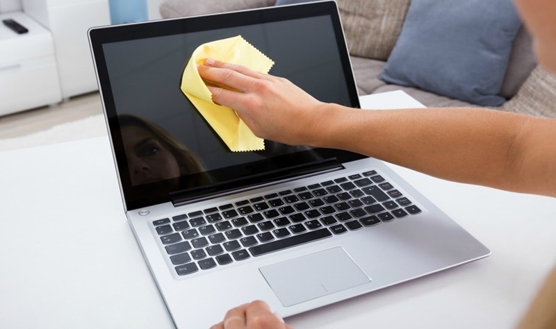cropped picture of a woman wiping the laptop screen