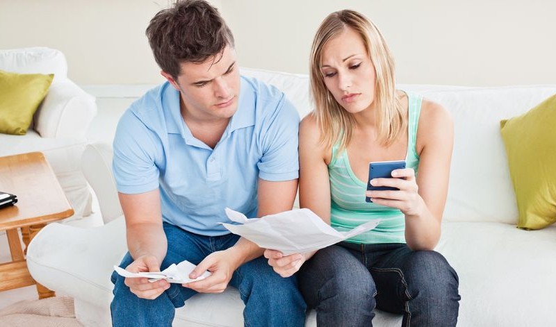a couple is sitting on a couch and reading a document
