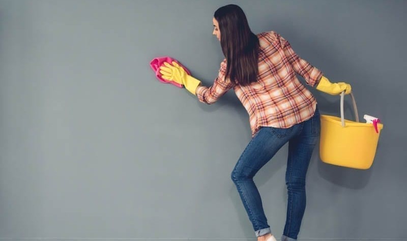 a beautiful young woman wiping painted walls with a cloth rag