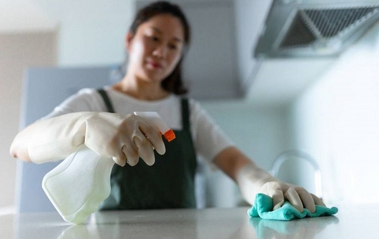 young woman disinfecting a surface with a spray