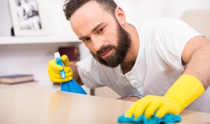 young bearded man disinfecting a surface