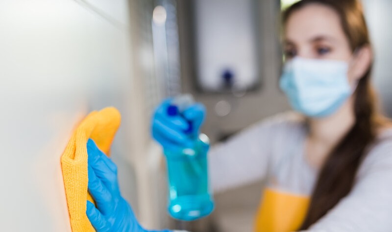 young woman with a mask disinfecting a surface
