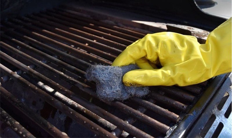cropped picture of a woman wiping a BBQ grill