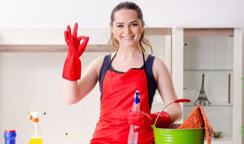 young woman wearing red apron ready to spruce up her house