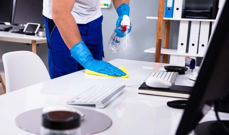 cropped picture of a professional disinfecting an office surface