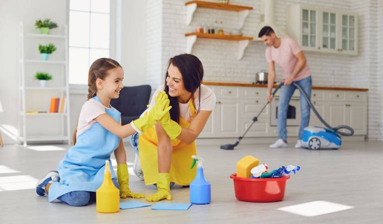 Man vacuuming floor, girl and woman in yellow gloves smiling with yellow, blue bottle and red basket