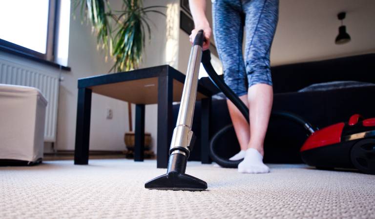 Woman vacuuming carpet in living room
