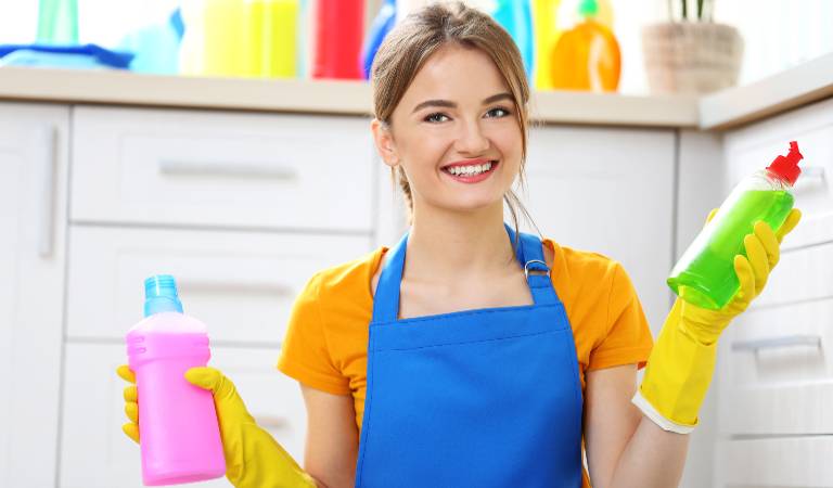 Woman holding pink bottle in one hand and green bottle in second hand and smiling