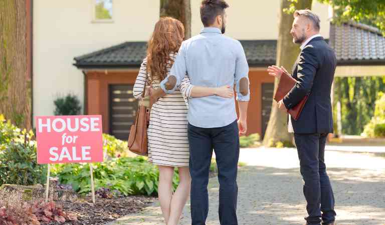 Man in black coat pant try to sell home to a couple.